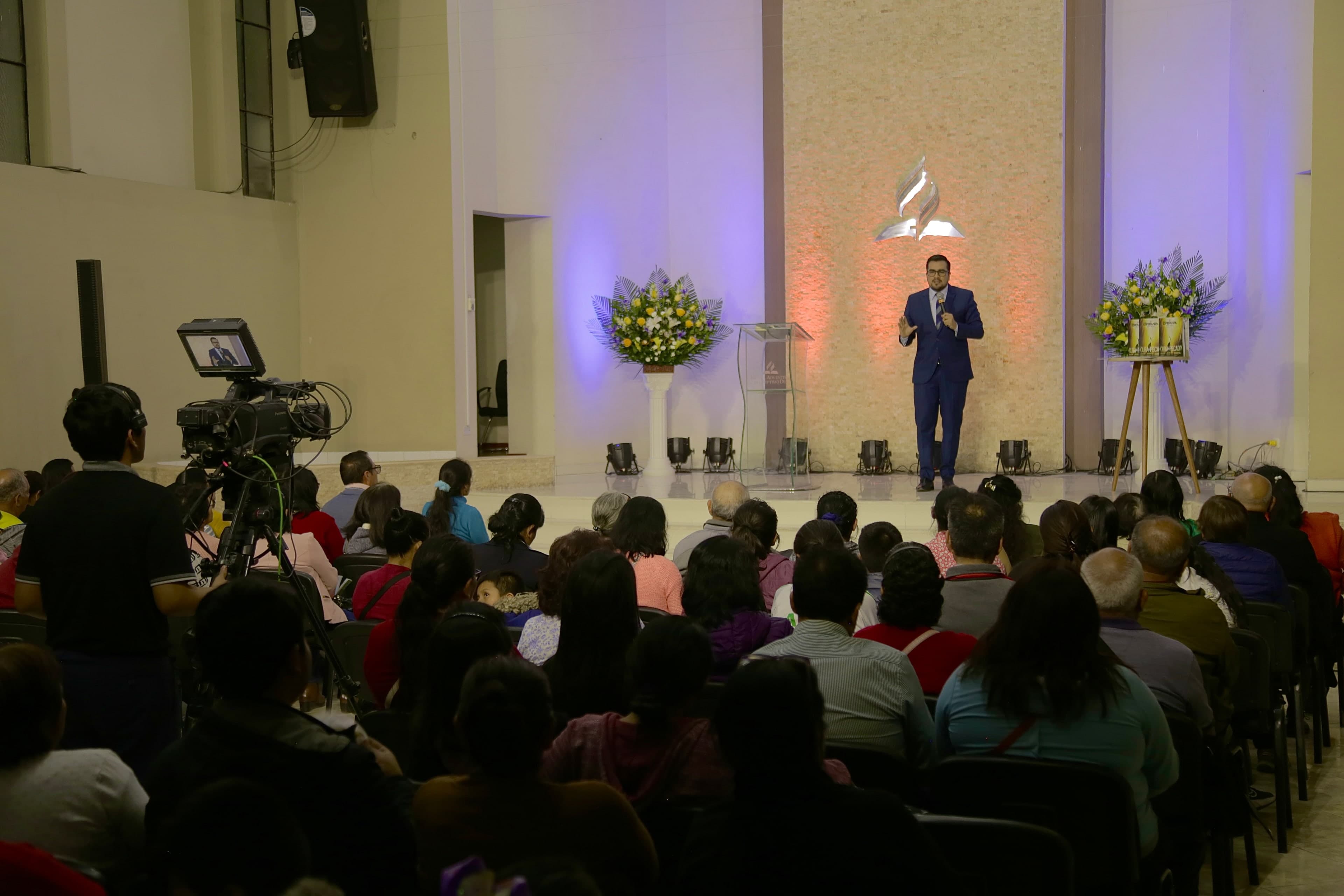 Anthony Araujo predicando sobre la plataforma de un templo, ante una congregación.