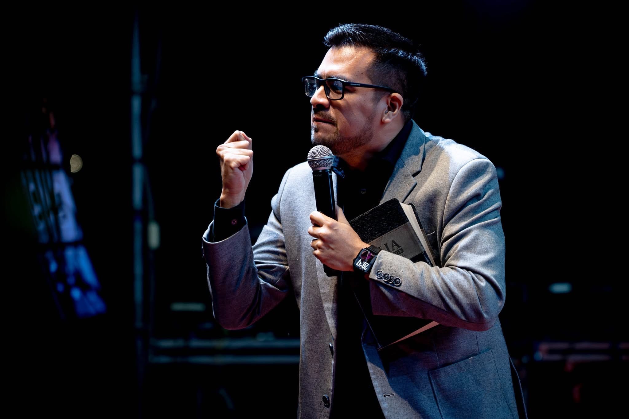 Anthony Araujo predicando con un micrófono, sosteniendo su Biblia.